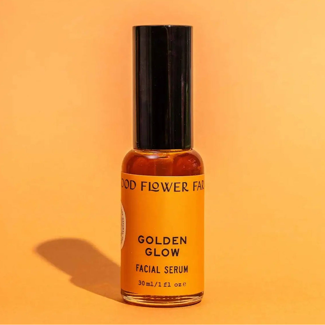 Facial serum bottle labeled 'Golden Glow' on an orange background