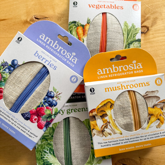 Ambrosia brand packaging for different types of produce on a wooden surface